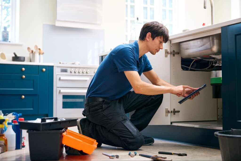 Professional plumber conducting kitchen repairs and maintenance in a modern home setting.