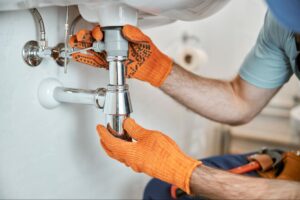 Fixing under-sink plumbing issues with professional tools and safety gloves.