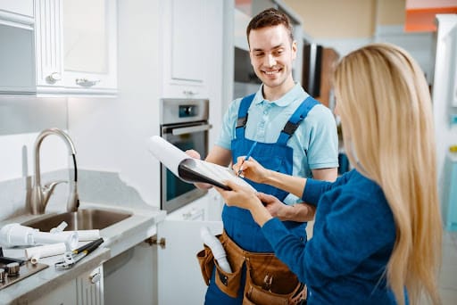 Professional plumber discussing project details with a client in a modern kitchen.