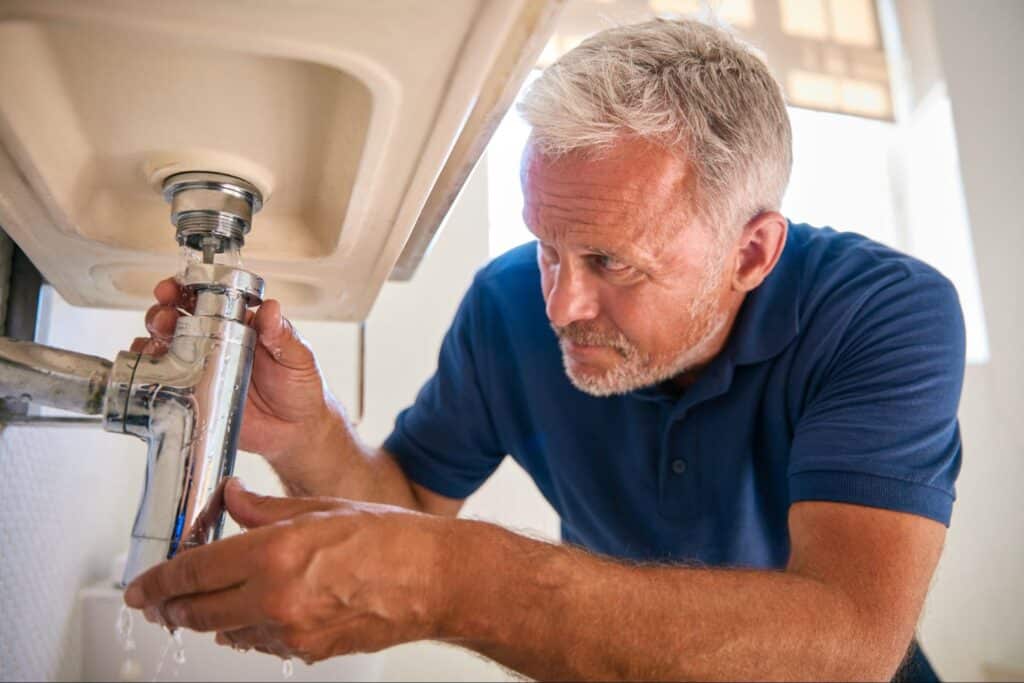 Plumber repairing sink plumbing, ensuring no leaks and proper installation for Residential Plumbing