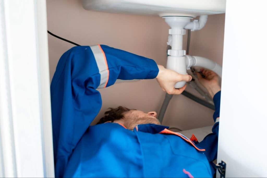 Plumber fixing under-sink piping for a residential plumbing repair.