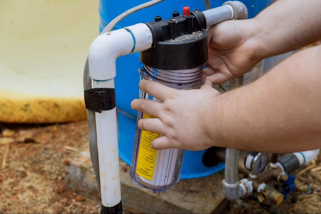 Hands installing a water filter for clean drinking water outdoors.