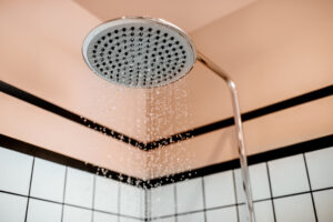 Modern shower head with flowing water droplets in a stylish bathroom setting.